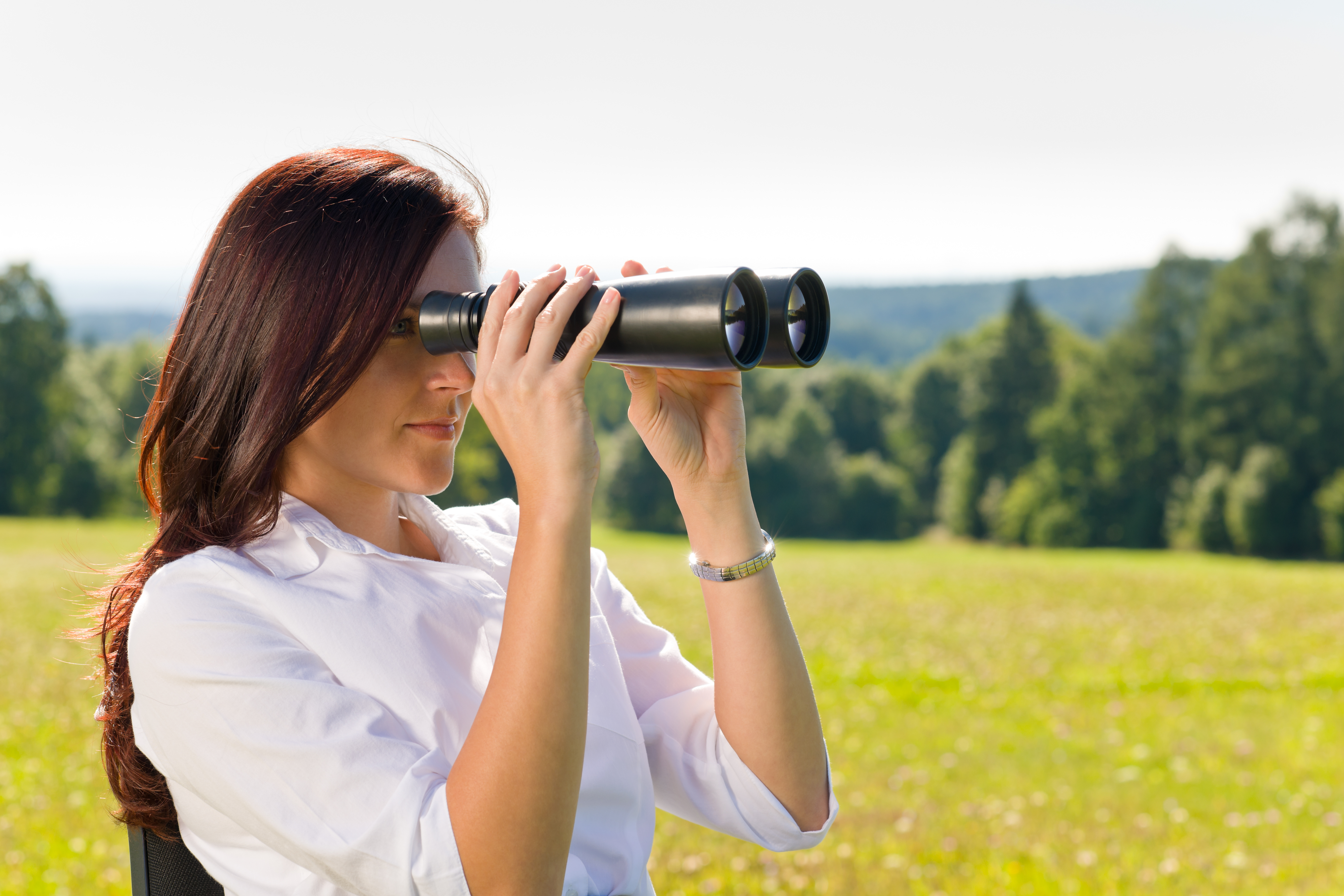 Business woman viewing outside with binoculars for p-card monitoring service