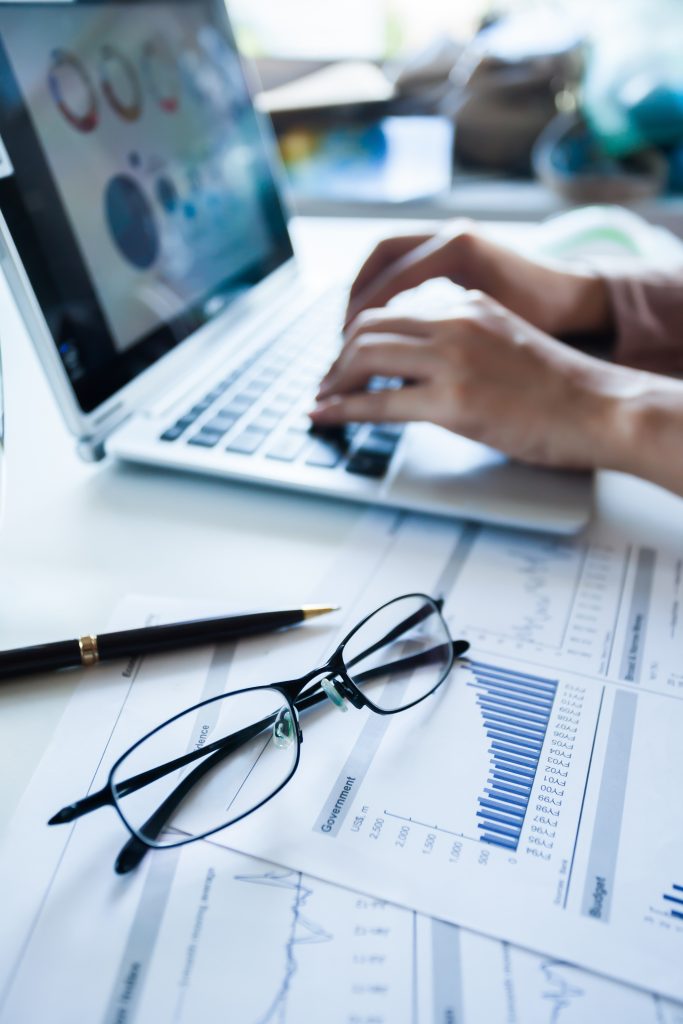 Businessman checking finance reports on the paper and laptop.