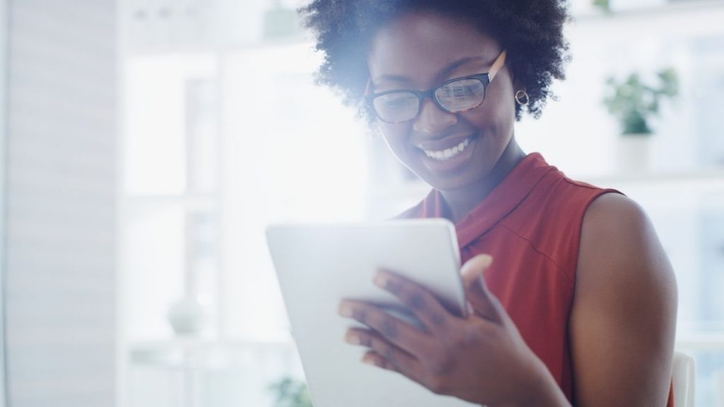 An Accounts Payable employee smiling with a tablet in hand - ready to implement a paperless accounts payable process